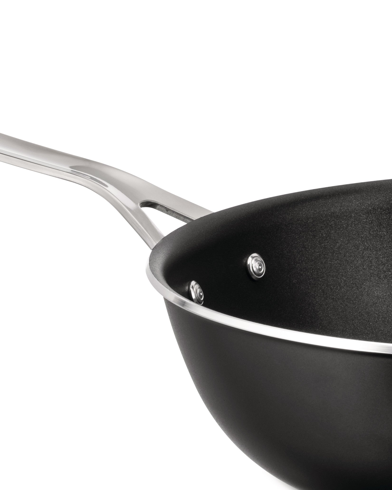 Black non-stick pan by Alessi with a polished silver handle and rim, shown in an angled close-up.