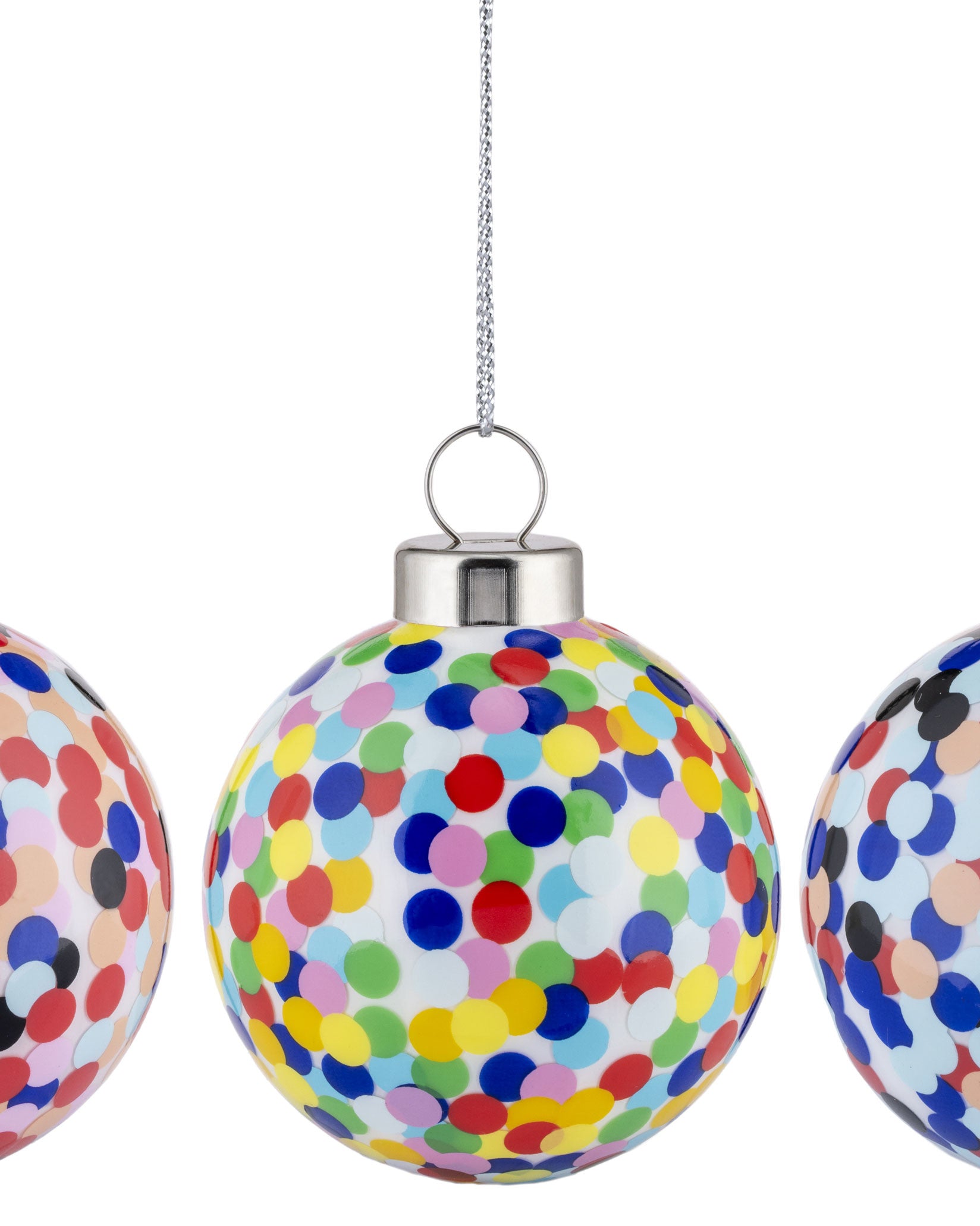 Multi-colored confetti Christmas ornament by Alessi, hanging by a silver chain, flanked by two partially visible ornaments.