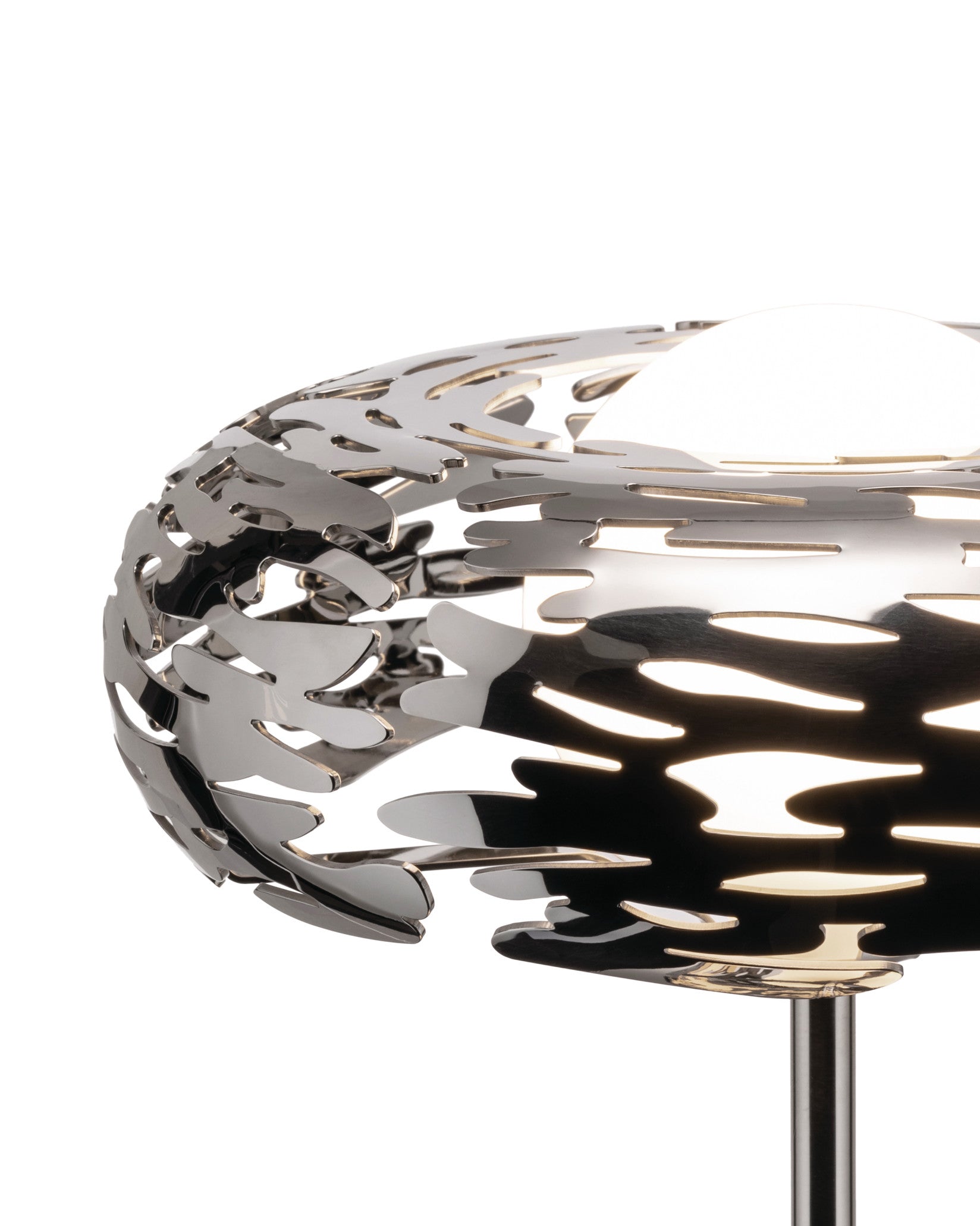 Polished silver metal lamp by Alessi with an intricate laser-cut bark-like pattern, illuminated from within.
