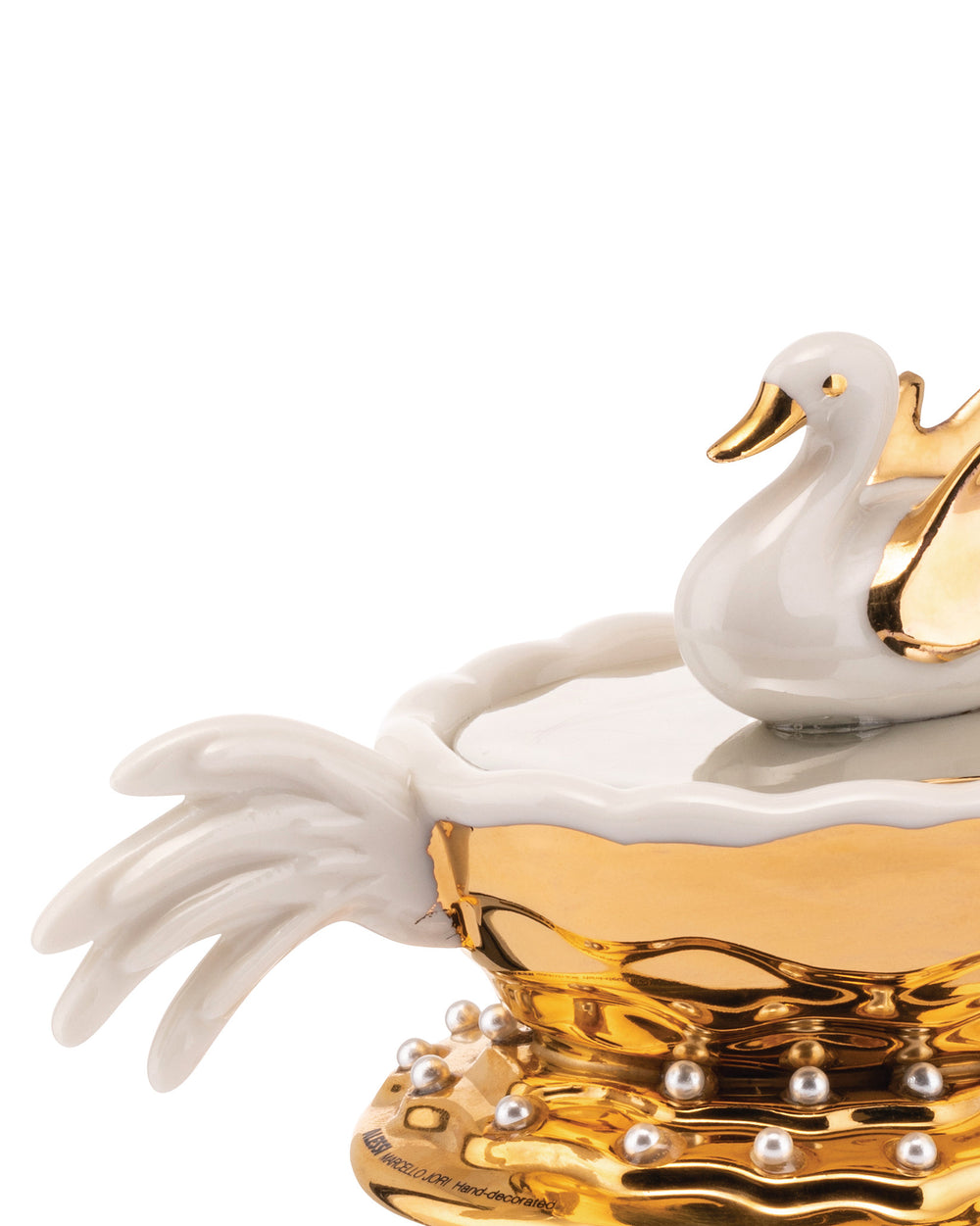 Cropped close-up of a white and gold swan decorative object by Alessi, with a wavy golden base adorned with pearls.