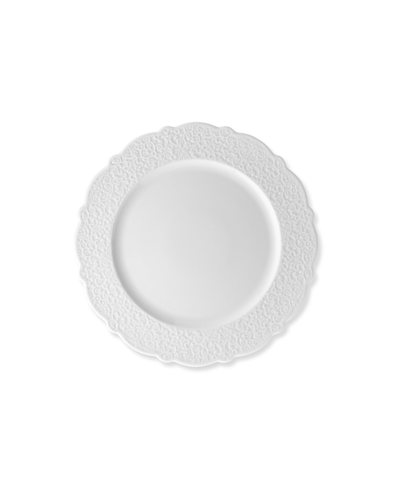 White plate by Alessi with ornate embossed swirl patterns and scalloped edges.