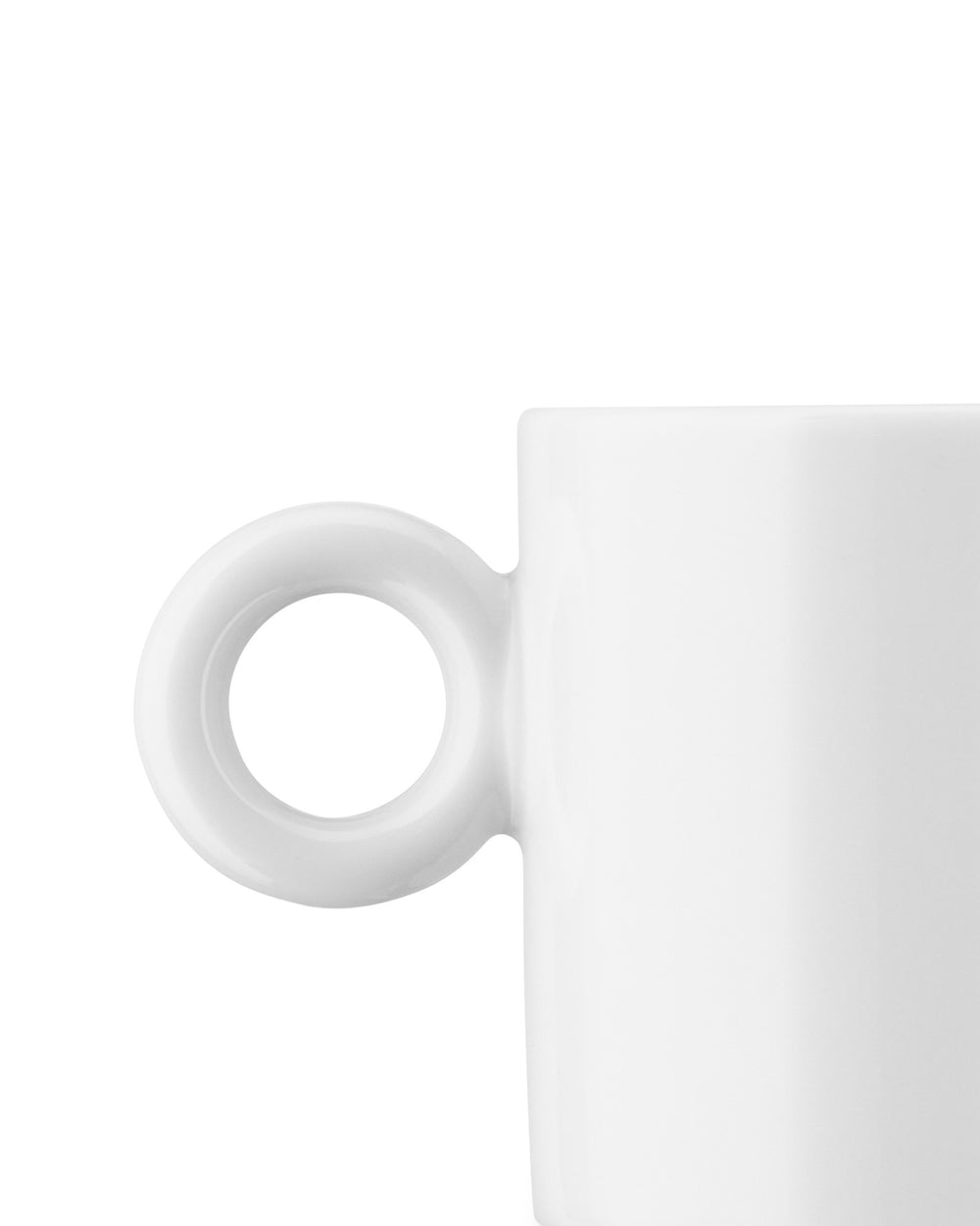 White ceramic mug by Alessi with a large, round, hollow handle, shown in a cropped side view.