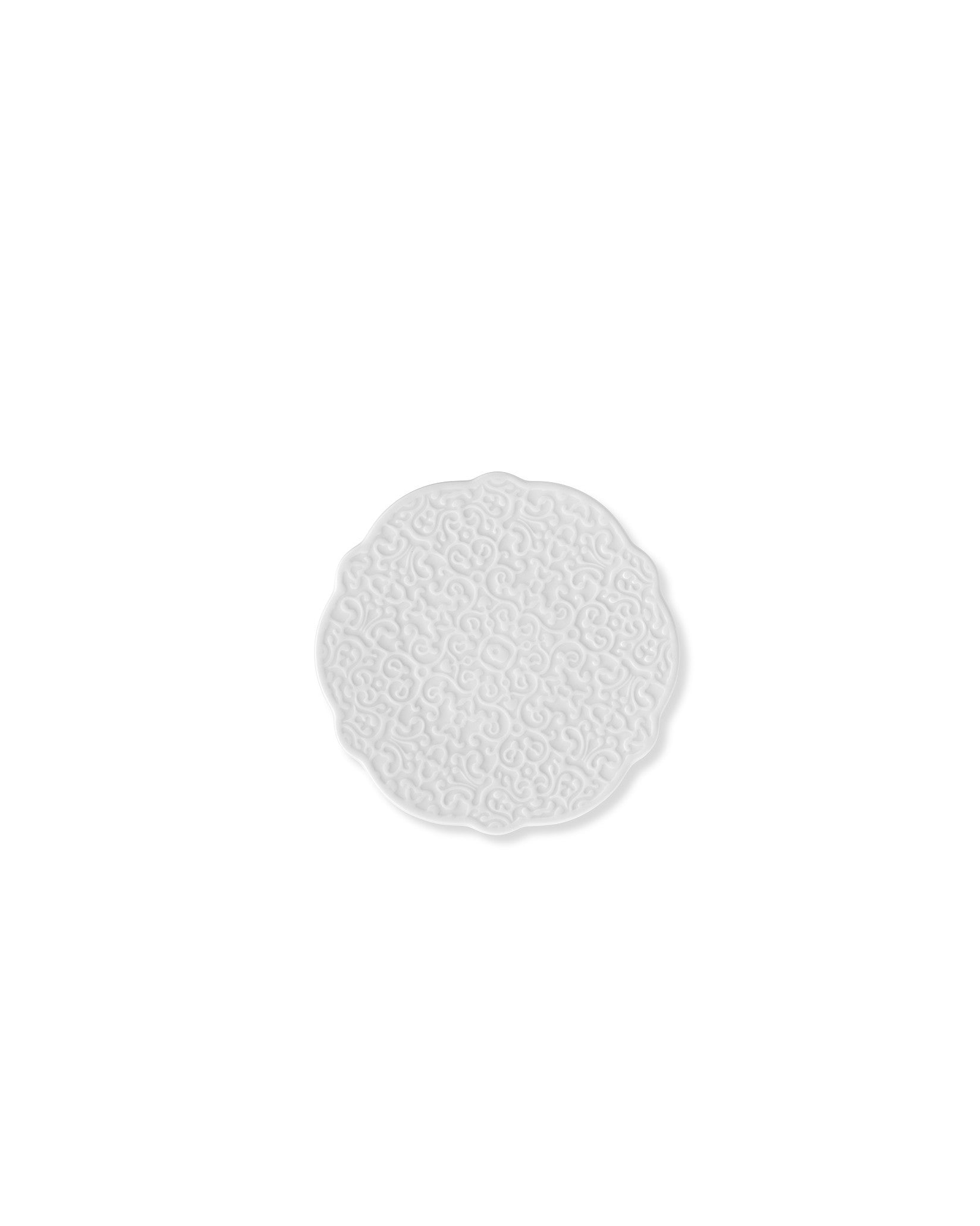 White round coaster by Alessi with a raised intricate scrolled pattern and scalloped edge.