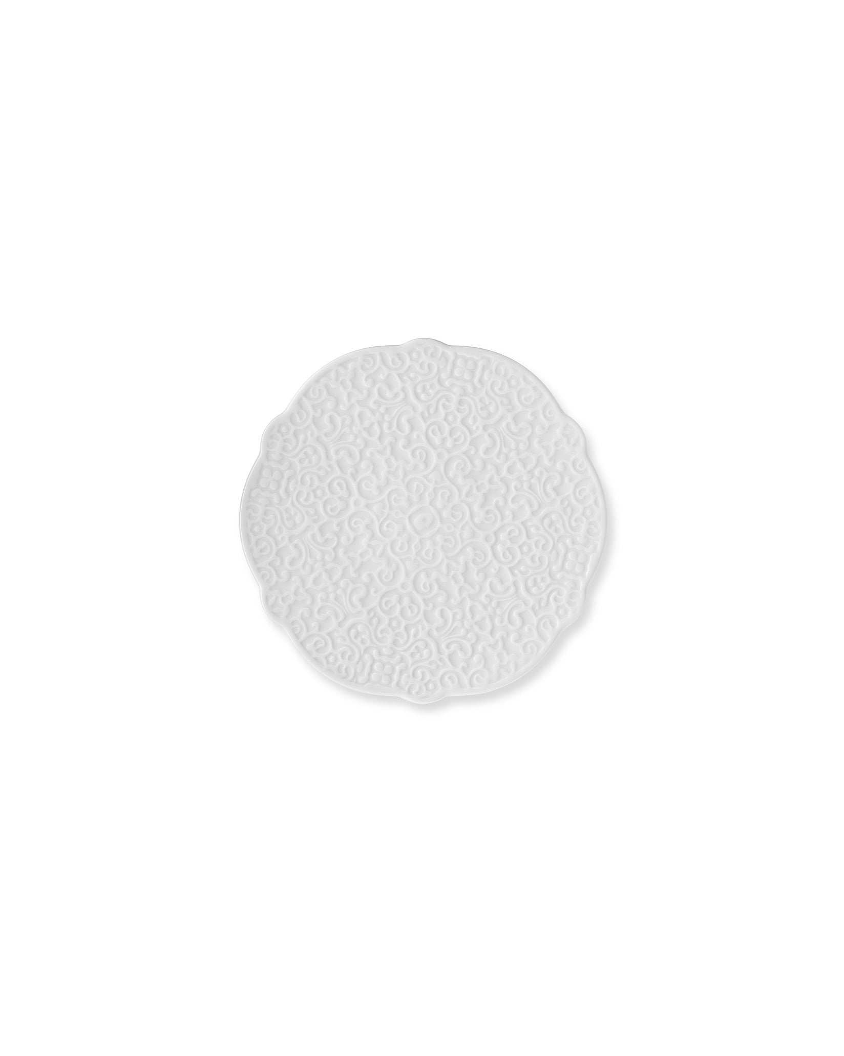 White decorative plate by Alessi with an embossed scrollwork pattern and scalloped edge.