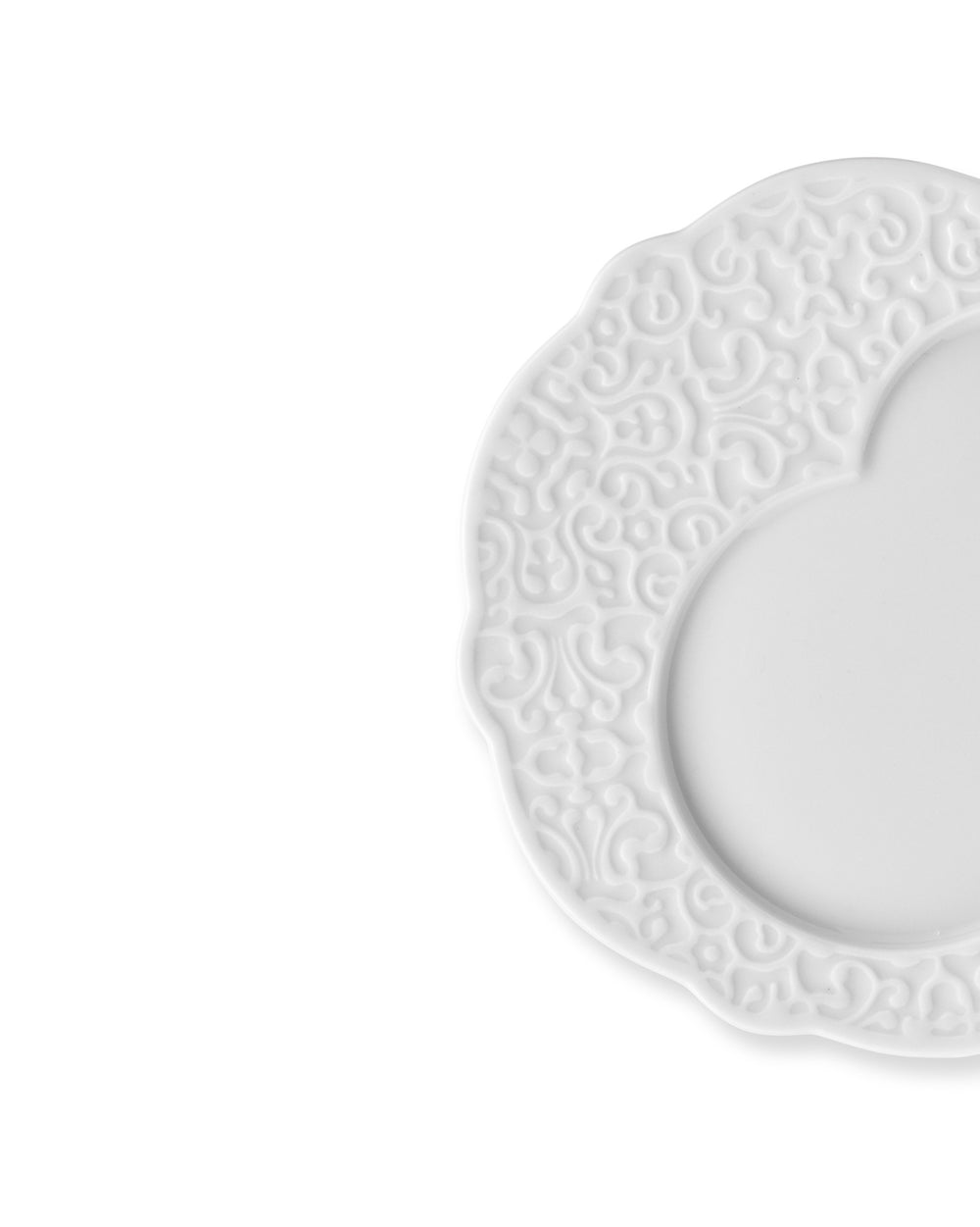 White plate by Alessi with scalloped edges and an embossed swirling pattern on the rim, cropped.