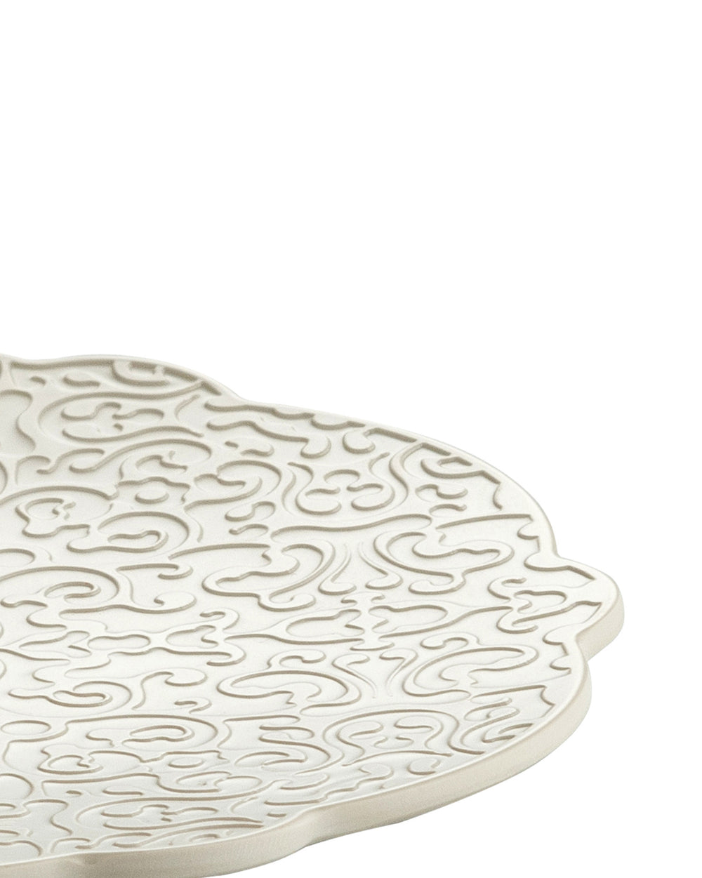 White decorative platter by Alessi, featuring an ornate, raised swirling pattern, cropped view.