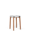 Modern stool by Alessi featuring a shiny chrome seat with wavy contours and four natural wood legs.