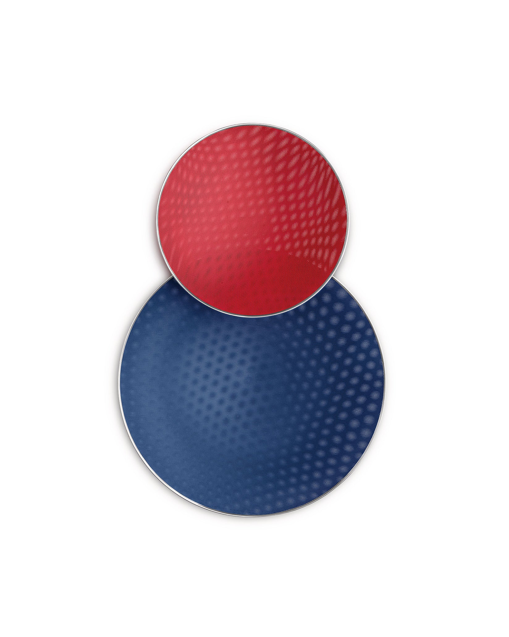 Two stacked red and blue circular dishes by Alessi with dotted textured surfaces and silver rims.