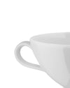 White ceramic cup by Alessi, a close-up cropped view showing the handle and rim.