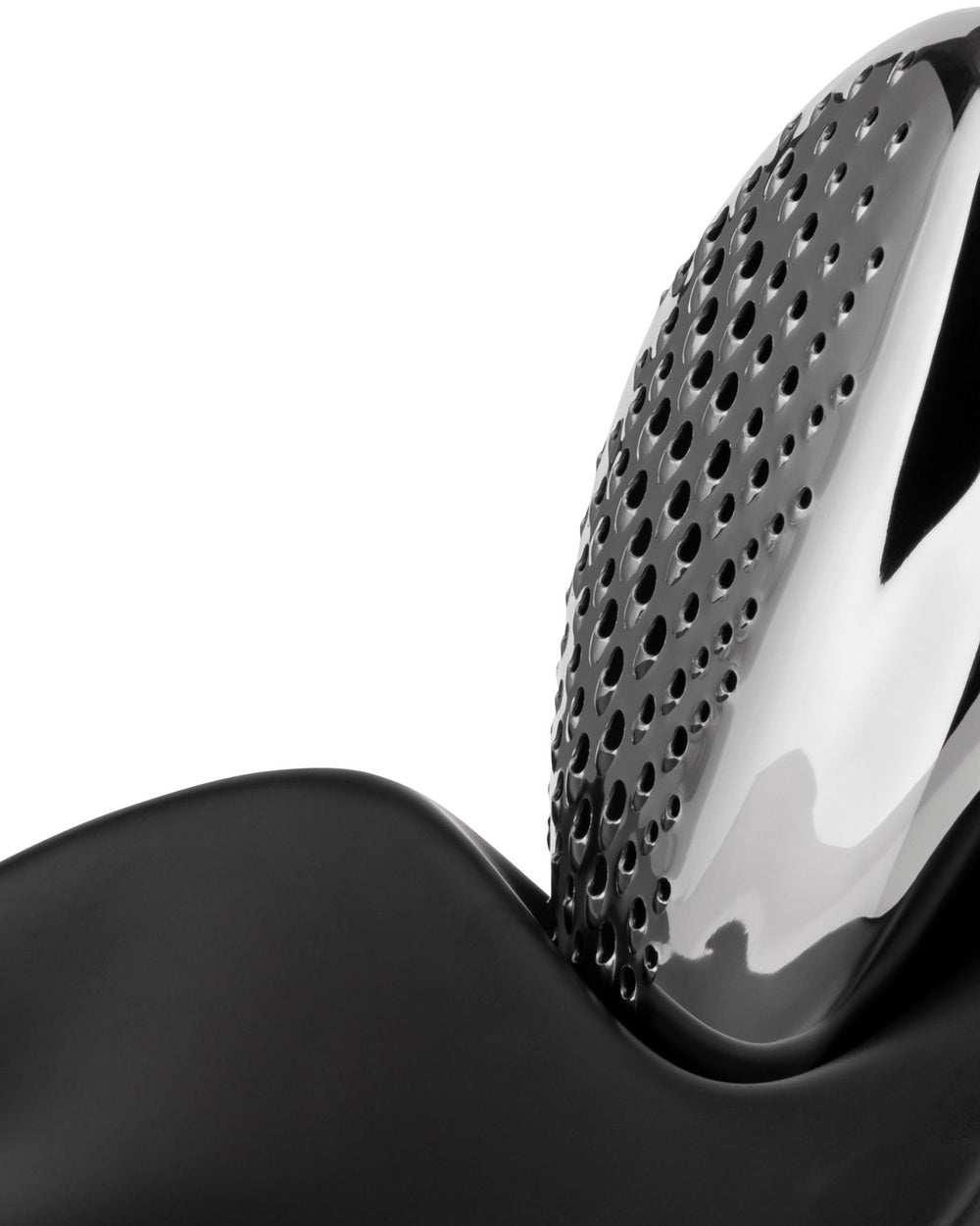 Silver metal grater by Alessi with a perforated surface, resting on a matte black base, close-up.