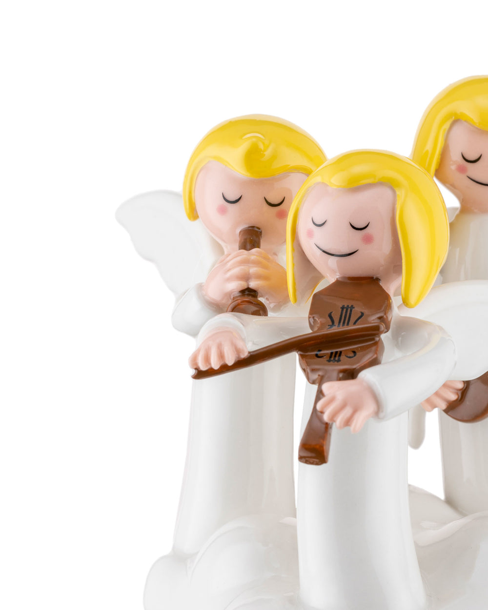 Three white angel ornamental figurines by Alessi, with yellow hair, playing brown flute and violin instruments.