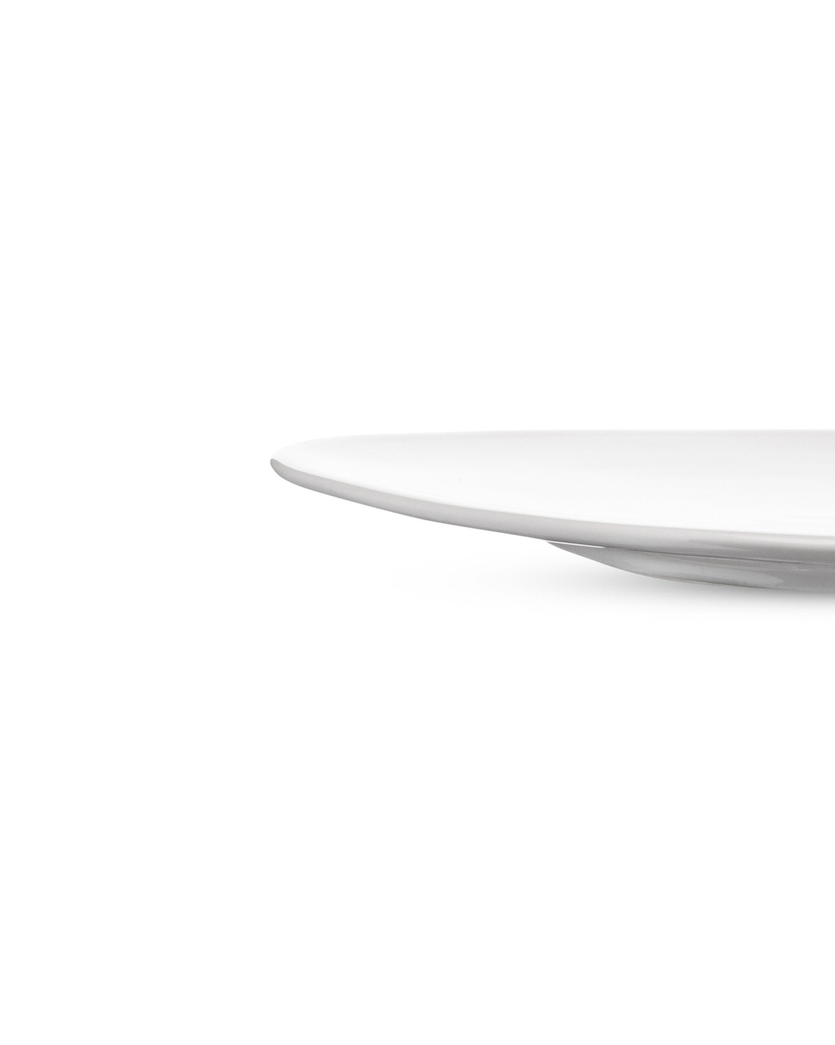 White plate by Alessi, a cropped side view highlighting its elegant, curved edge.