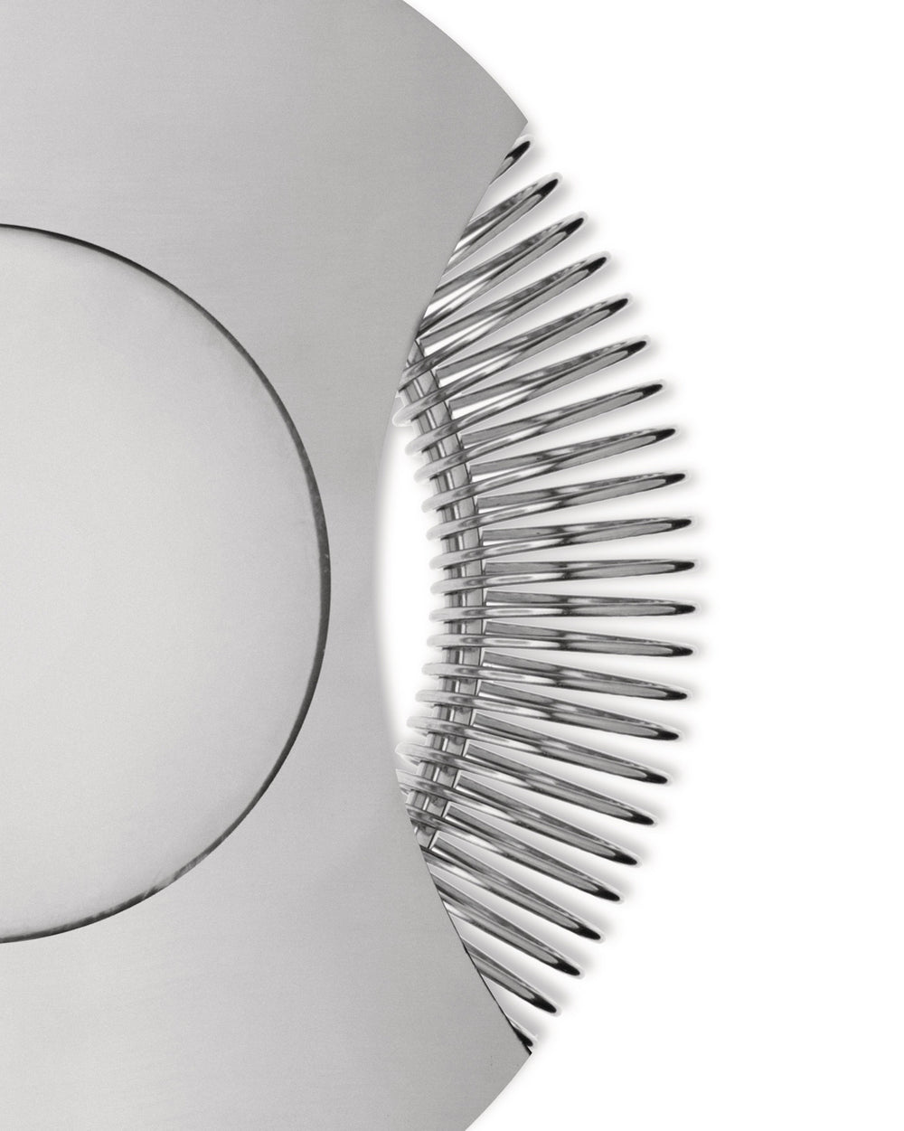 Polished silver tending box by Alessi, captured in a close-up showing its distinct curved edge with radiating metal elements.