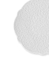 White embossed plate by Alessi with a scalloped edge and intricate scroll pattern, cropped.