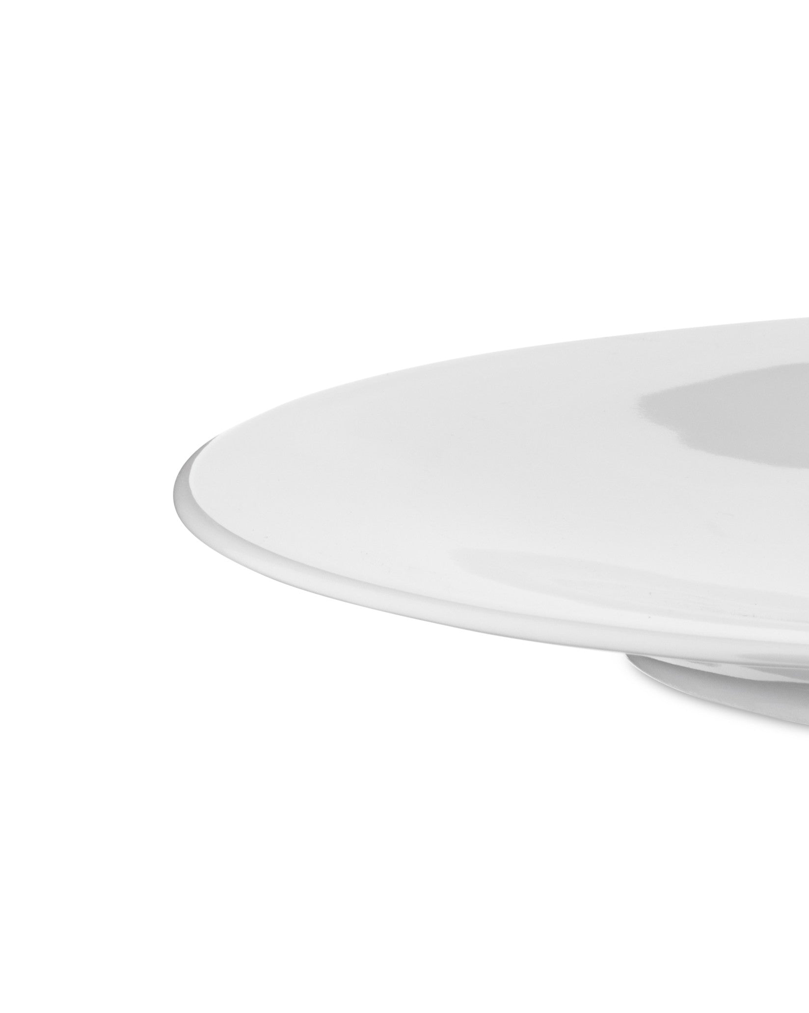 Cropped view of a minimalist white plate by Alessi, featuring a smooth, glossy surface and curved edge.