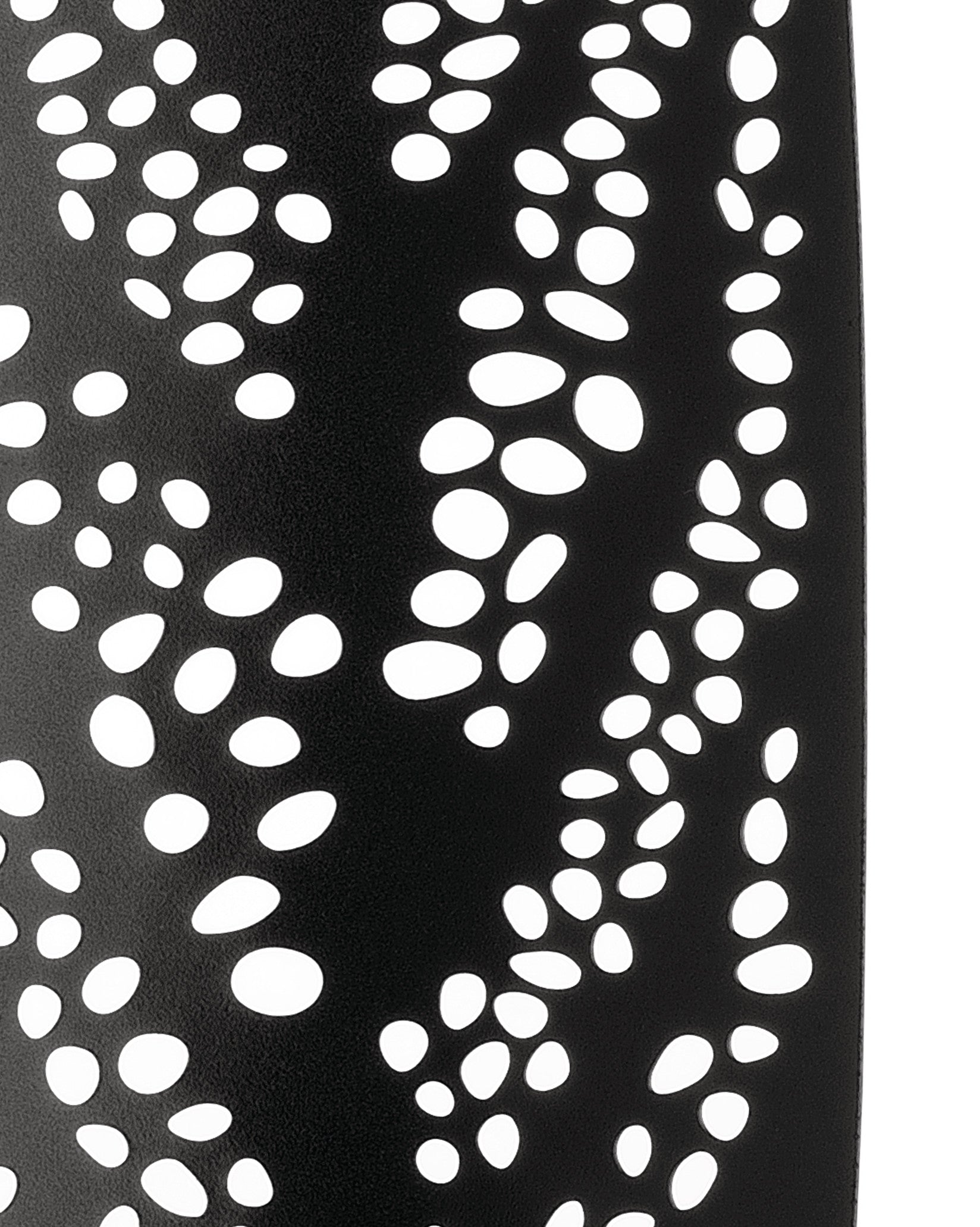 Black perforated decorative object by Alessi with flowing white oval cutouts and a matte texture, curving upward.