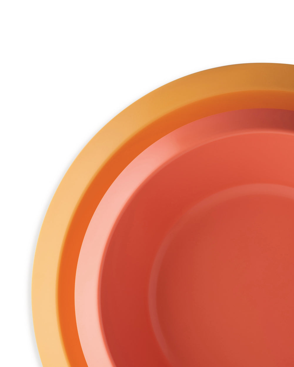 Nested colorful kids bowls by Alessi, in shades of orange and coral, viewed from above.
