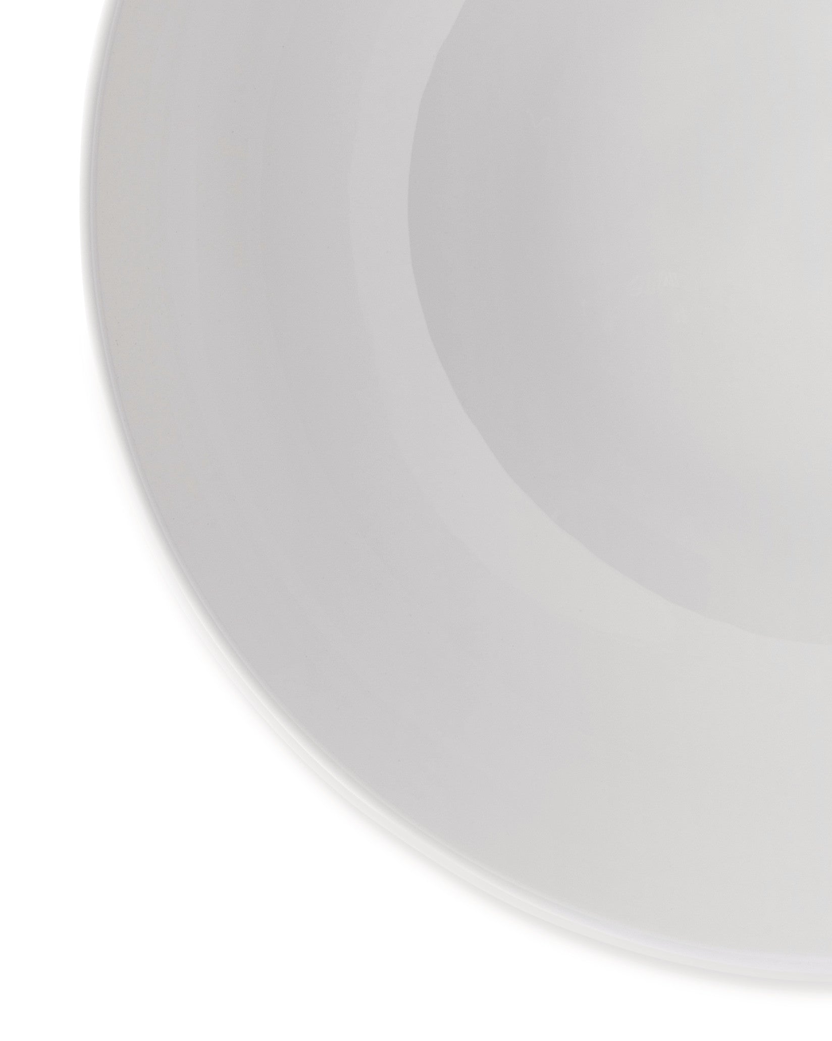 White ceramic dish by Alessi, with a smooth, reflective surface and gently curved rim.