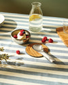 Silver serving spoon by Alessi, resting on a woven coaster next to ice cream and berries.