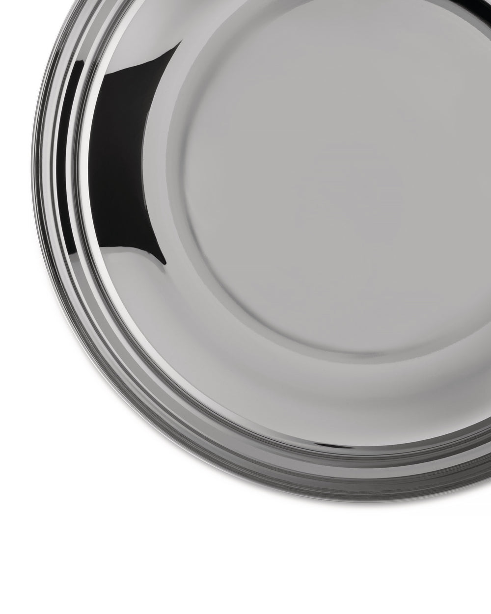Round silver metal serving tray by Alessi with concentric ridges and a reflective surface, cropped.