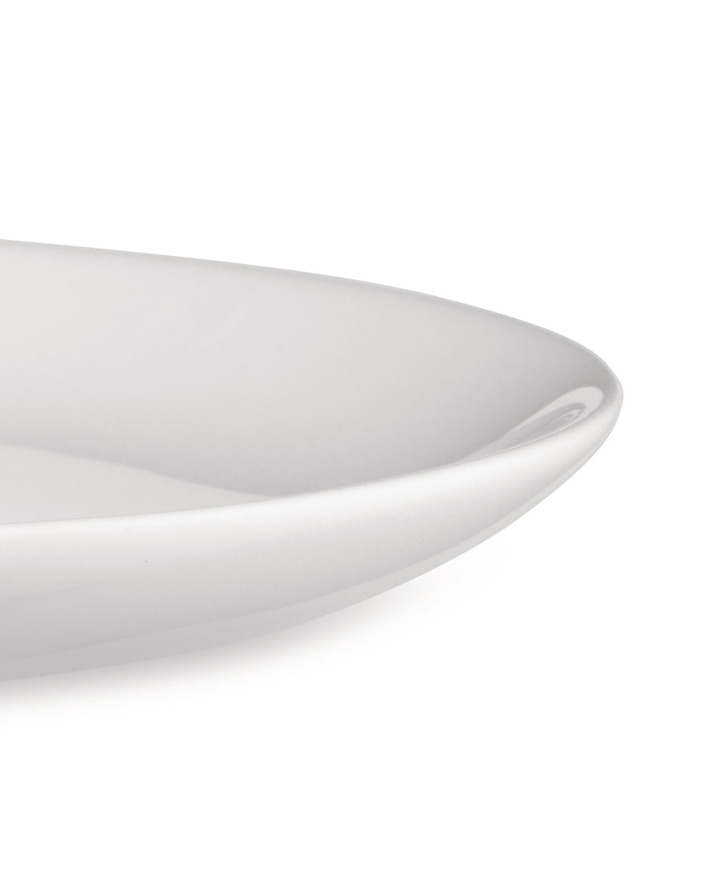 A white, glossy serving dish by Alessi with gently curved edges, shown in a close-up, cropped view.