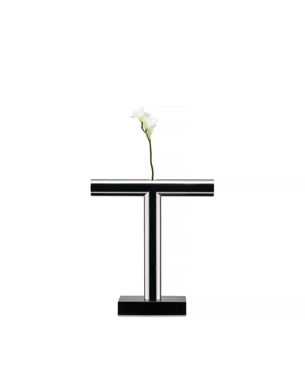 Chrome T-shaped vase by Alessi with a black rectangular base, holding a single white flower.