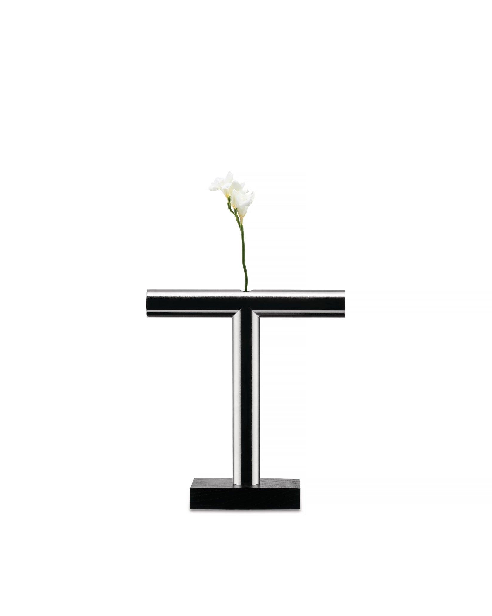 Chrome T-shaped vase by Alessi with a black rectangular base, holding a single white flower.
