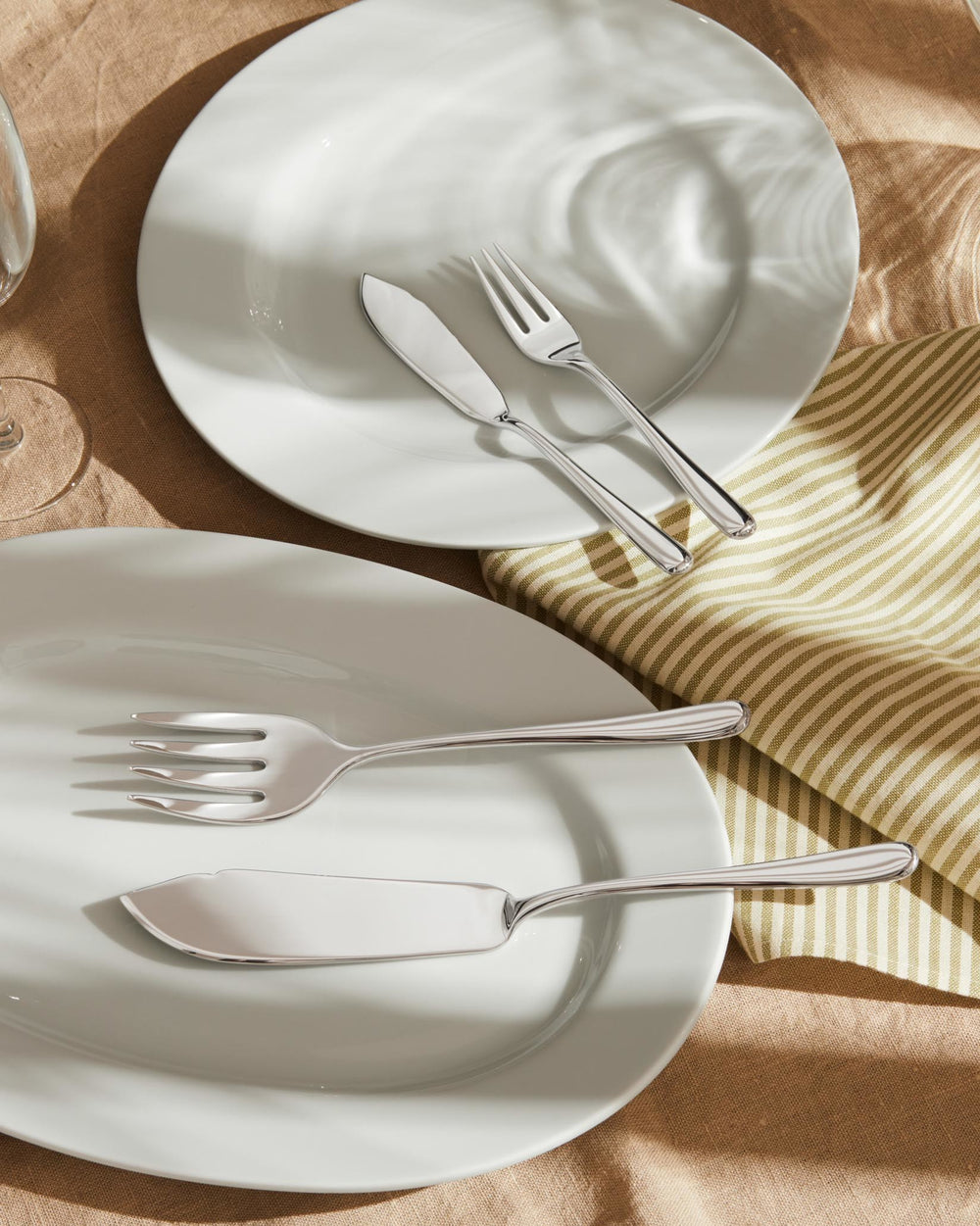 Silver Caccia cutlery set by Alessi, displayed on white plates and a striped napkin.