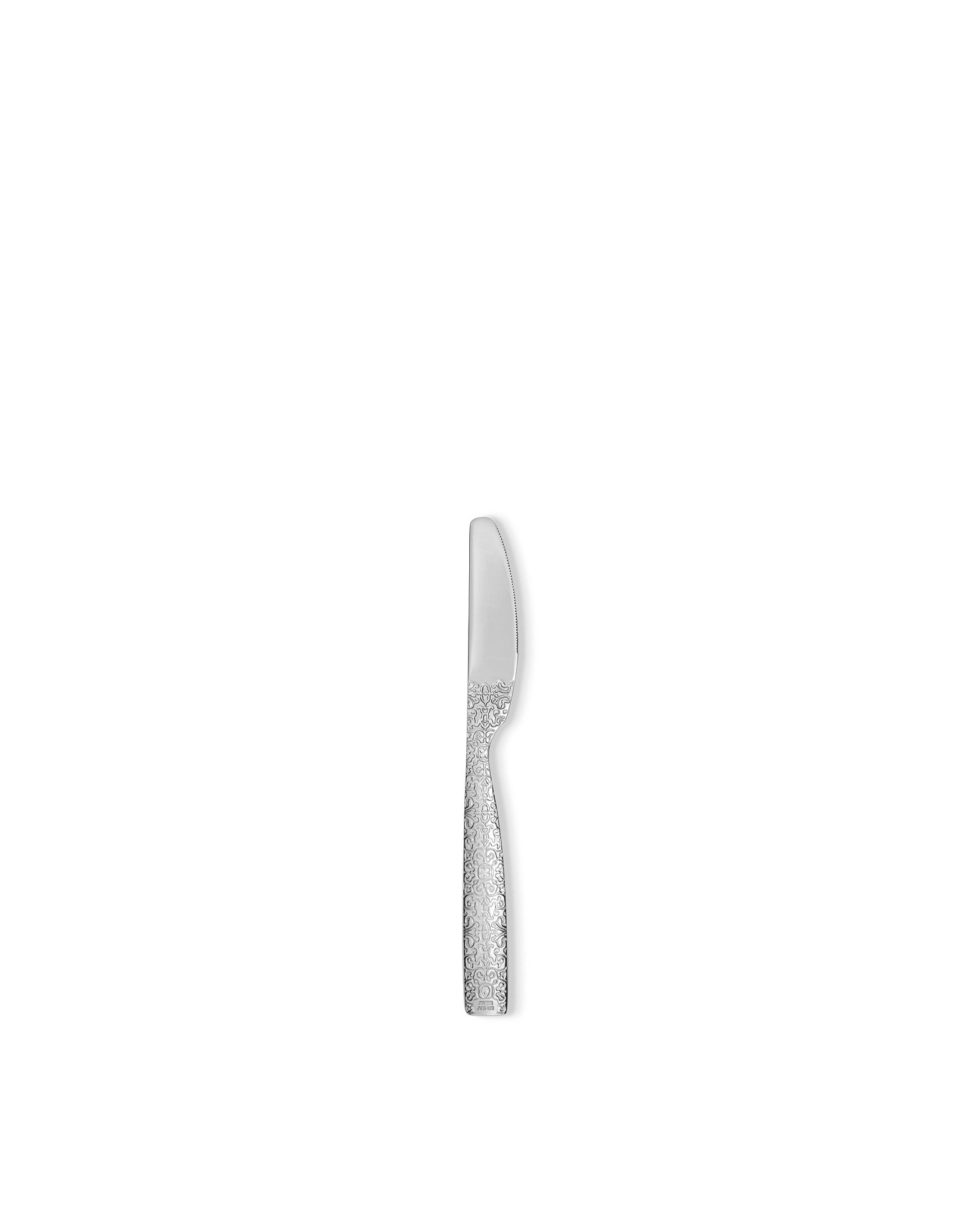 Silver knife by Alessi, with a serrated blade and intricate scrollwork on the handle, shown in a side view.