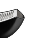 Black and silver grater by Alessi with a textured, curved body and perforated metal grating surface, shown cropped.