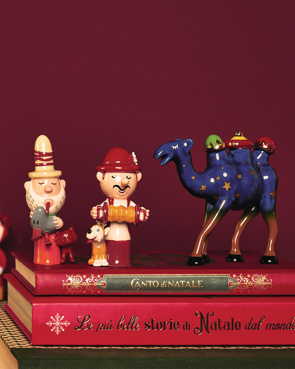Colorful ceramic Christmas Trino decorations by Alessi, featuring a man playing a bird, an accordionist with a dog, and a starry blue camel.