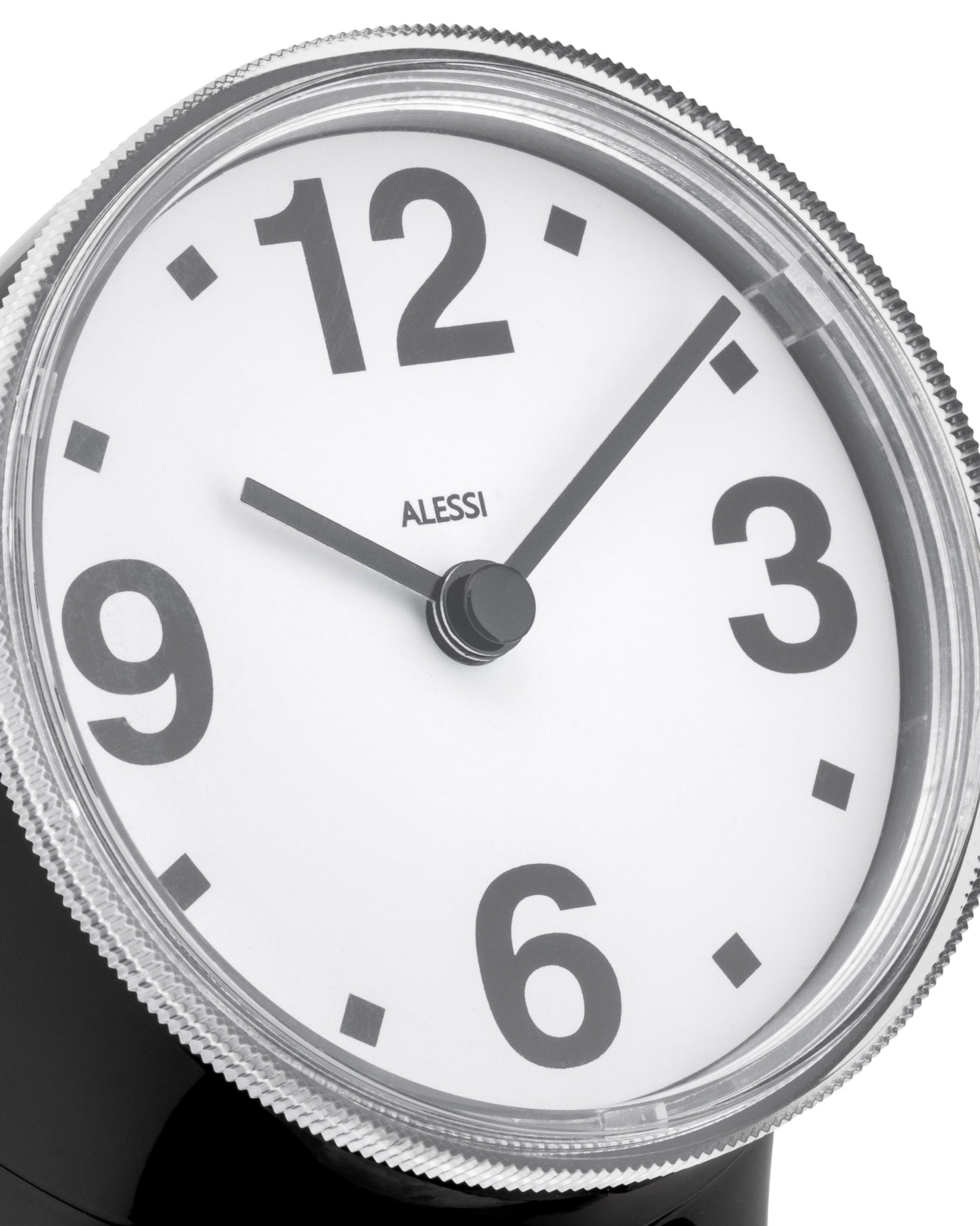 Black and white alarm clock by Alessi with bold grey numbers, a silver corrugated bezel, and black hands.