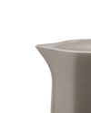 Matte taupe ceramic pitcher by Alessi with a modern angular spout, cropped close-up.