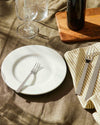 Santiago stainless steel cutlery by Alessi, with a fork on a white plate and knife on a striped napkin.