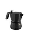 Black faceted Moka pot by Alessi, with a sturdy handle and gold pressure valve, on a white background.