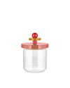 Clear glass storage jar by Alessi with a rose-colored lid, gold disk, and red spherical knob handle.