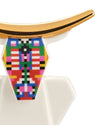 White cow figurine with golden horns by Alessi, featuring a colorful pixelated geometric pattern on its face, cropped view.