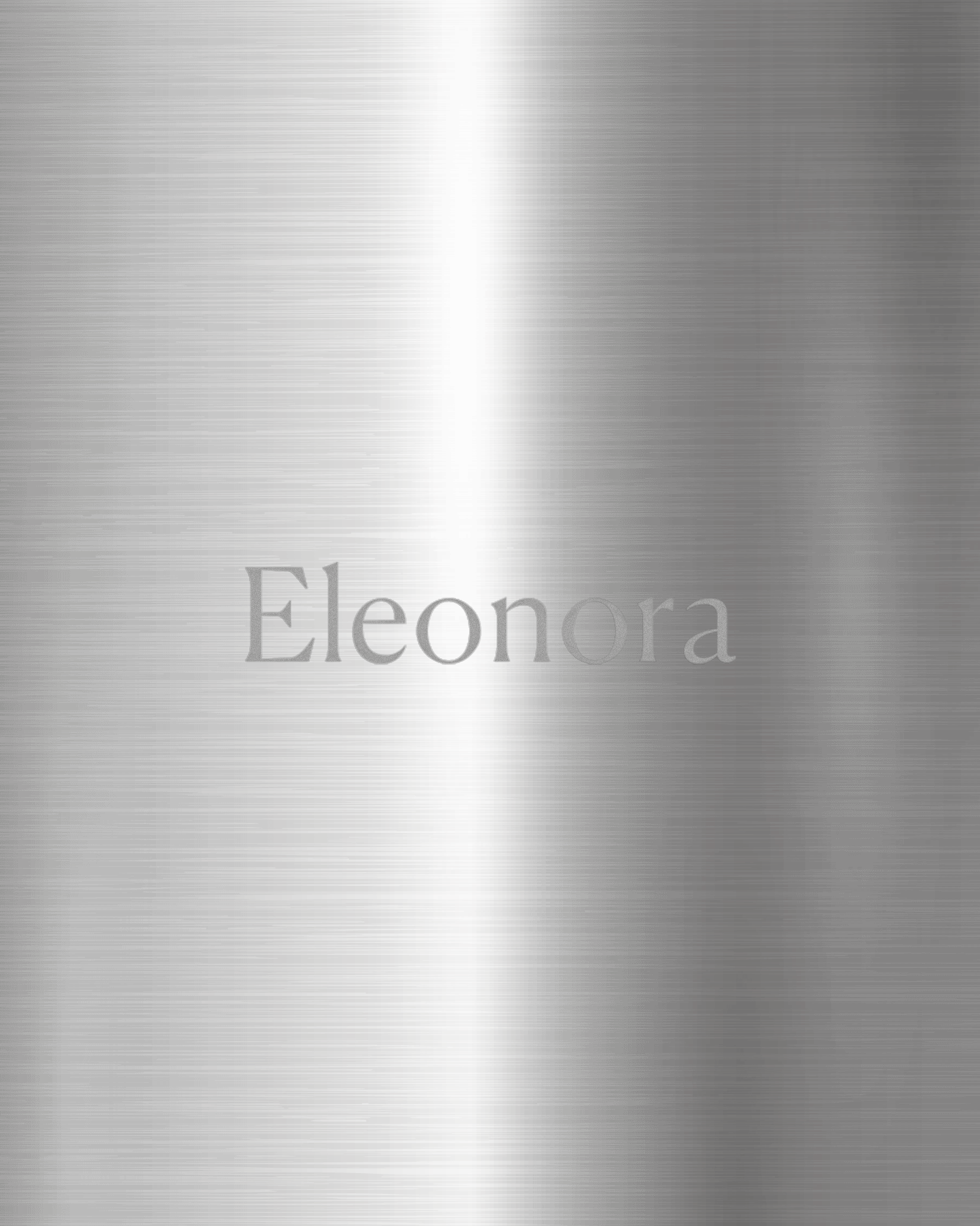 Engraved brushed metal sample by Alessi featuring the name 'Eleonora' in a silver serif font.