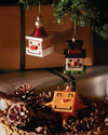 Cube-shaped Snow Cube Christmas ornaments by Alessi, featuring distinct designs like a snowman, a simplified face, and an orange star.
