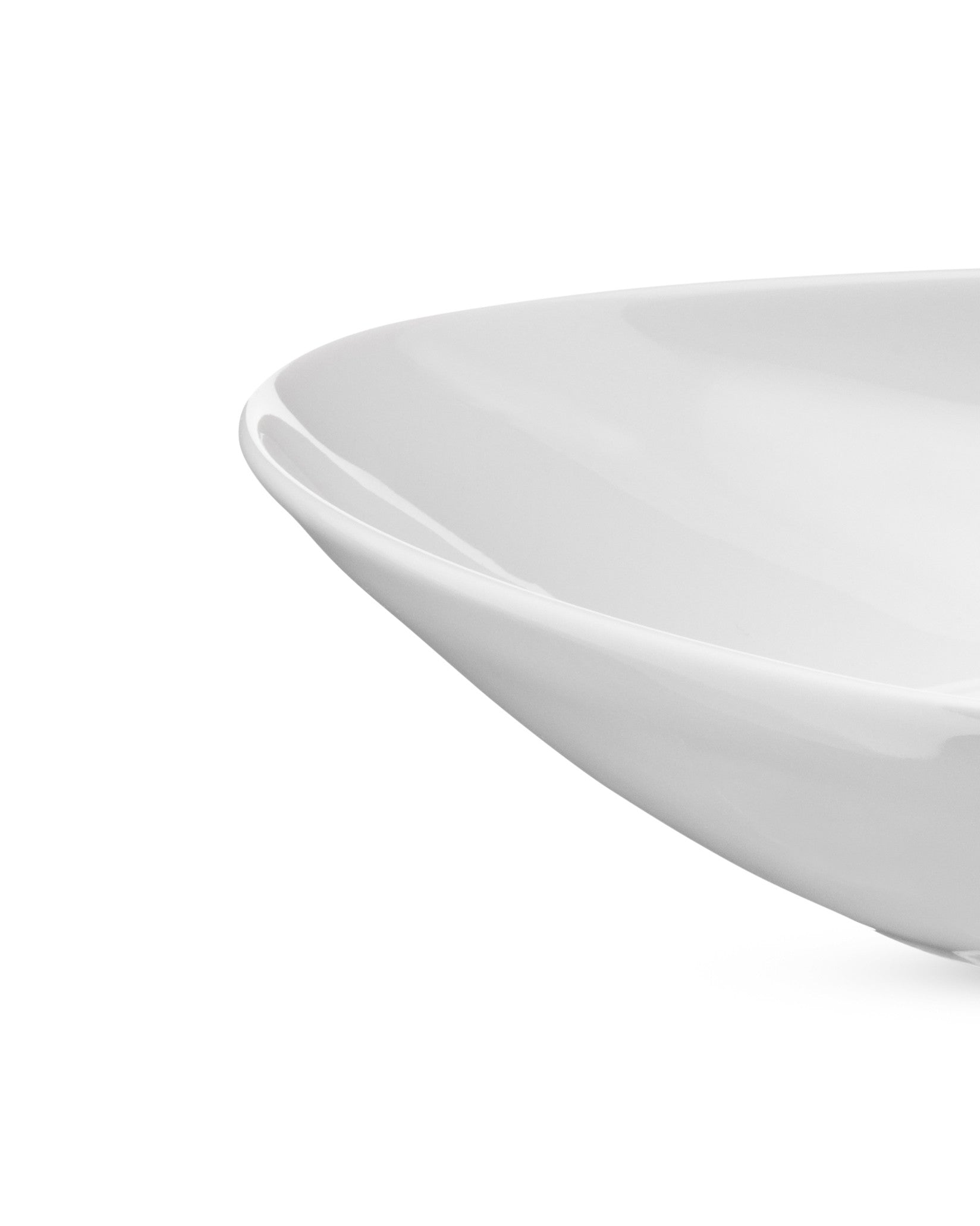 White shallow bowl by Alessi, a smooth, glossy ceramic piece with gently curved edges, close-up.