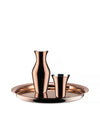 Reflective metallic copper drinking glass by Alessi, shown with a matching carafe and round serving tray.