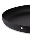Black round shallow dish by Alessi, with a dimpled matte texture and a silver brand plaque.