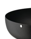 Black perforated bowl by Alessi with a silver logo badge, shown in a close-up, cropped view.