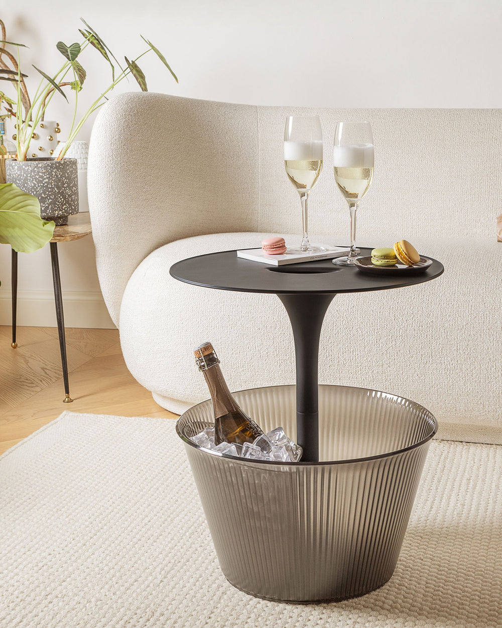 Matte black side table with smoked grey ribbed integrated ice bucket by Alessi, holding champagne and ice.