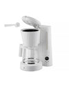 White ribbed coffee machine by Alessi with an open lid, glass carafe, and a measuring scoop.
