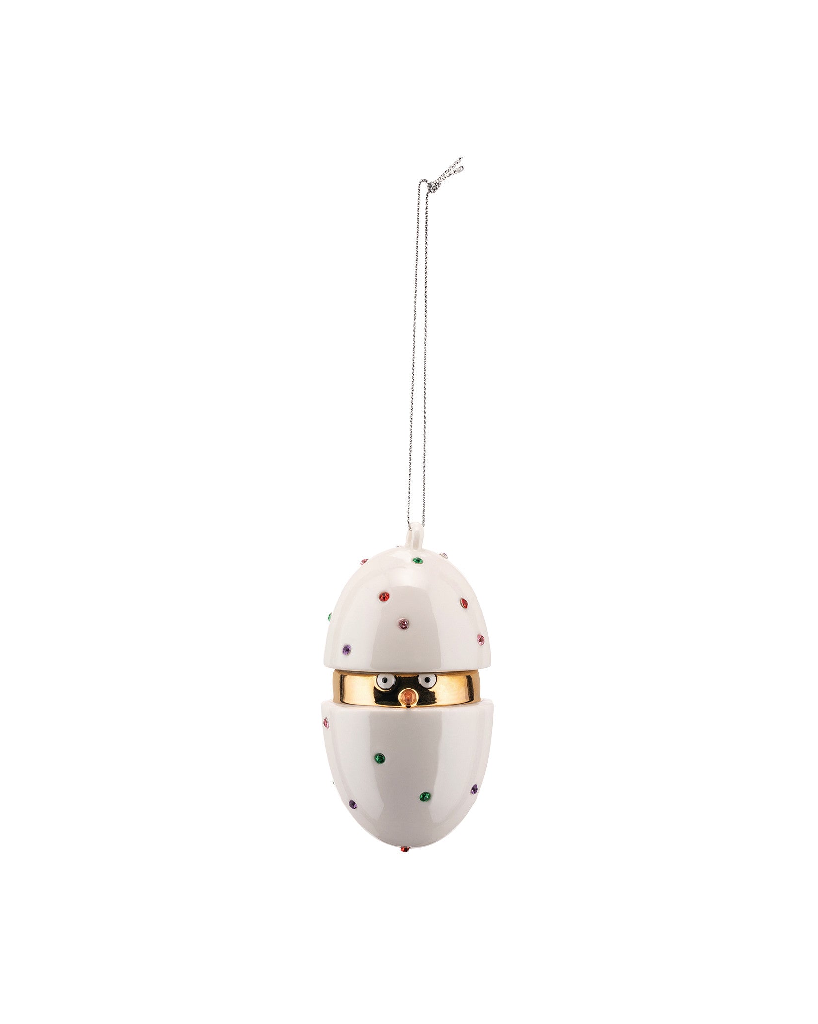 A white egg-shaped hanging ornament by Alessi, decorated with colorful studded dots, a gold band, and a chick's face peeking out.