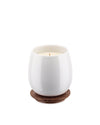 White ceramic candle by Alessi, resting on a brown wooden coaster with an engraved leaf pattern.