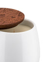 White ceramic candle with an etched wooden lid by Alessi, lid slightly ajar showing the wick and wax.