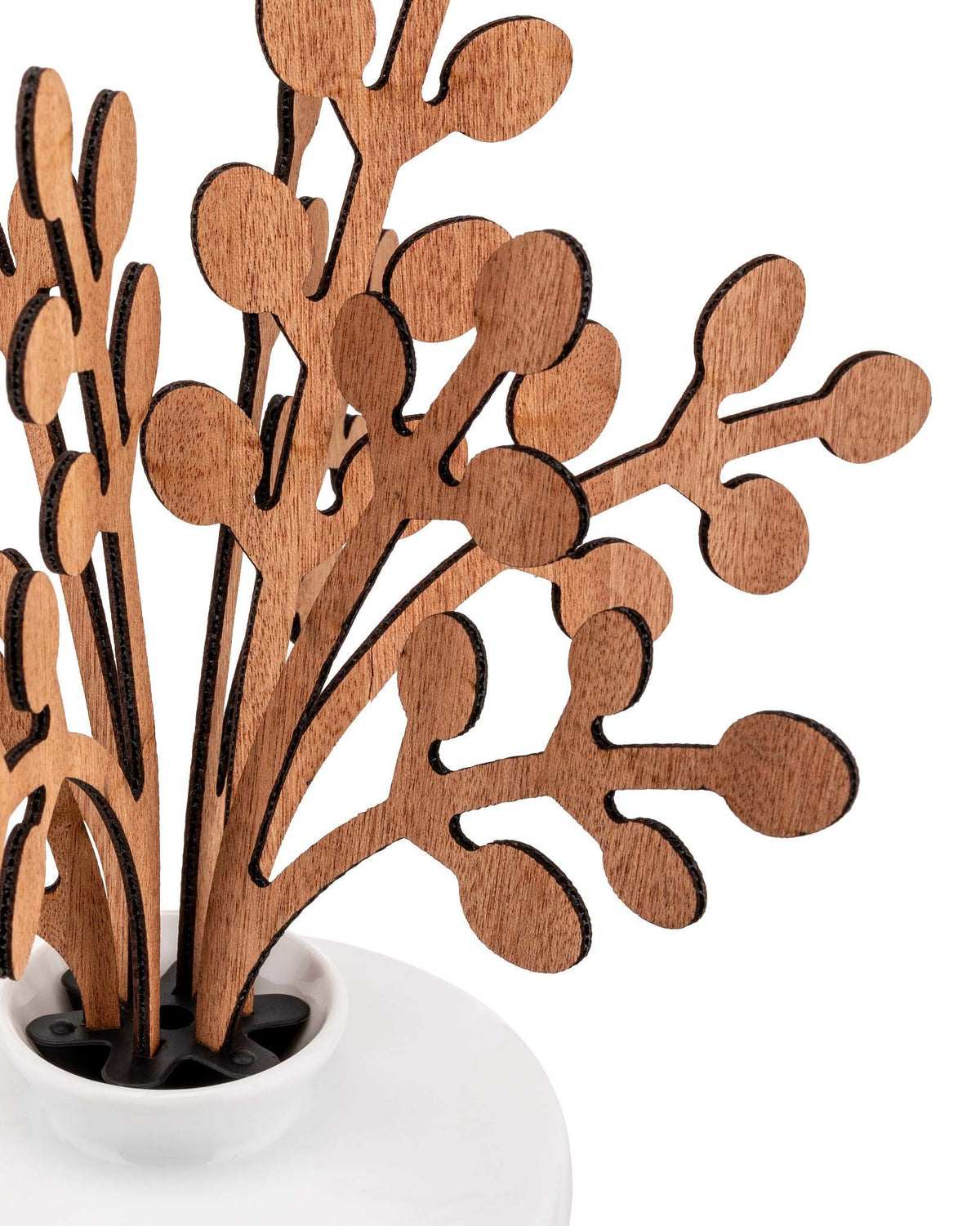Stylized wooden branches by Alessi, with dark burnt edges, arranged in a white ceramic pot.