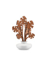 White ceramic diffuser with brown wooden monstera leaves by Alessi, standing upright on a white background.